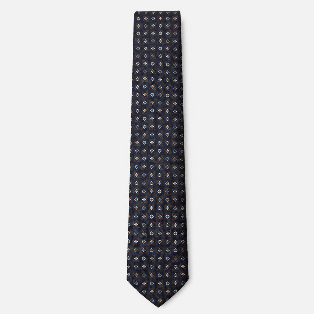 The Bolzano Tie – navy, gold and rust micro medallion silk tie on a light grey background