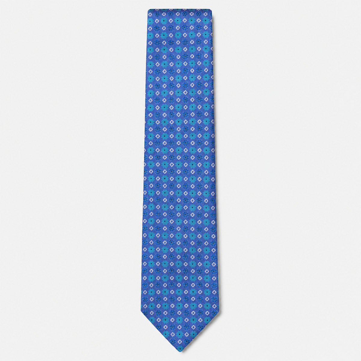 The Ferrara Tie, a royal blue silk tie with turquoise, lavender and white geometric motifs on a light grey background.