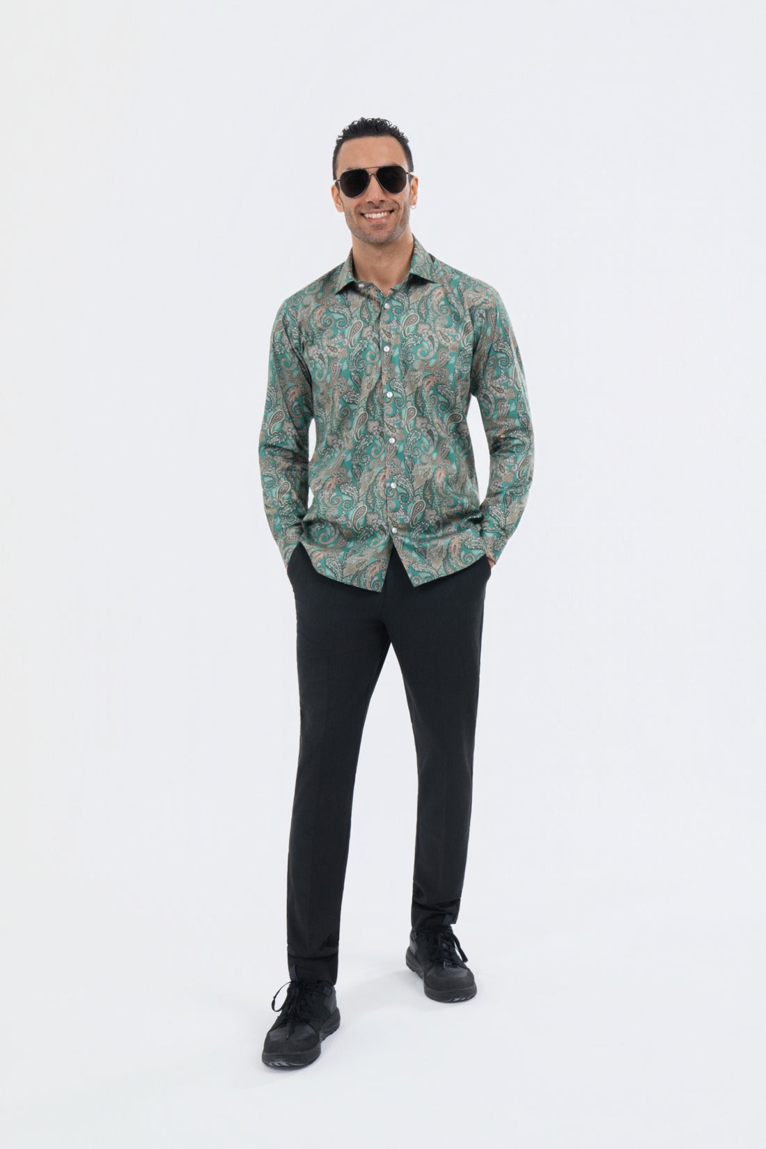 Male model wearing a sage green paisley shirt with black trousers.
