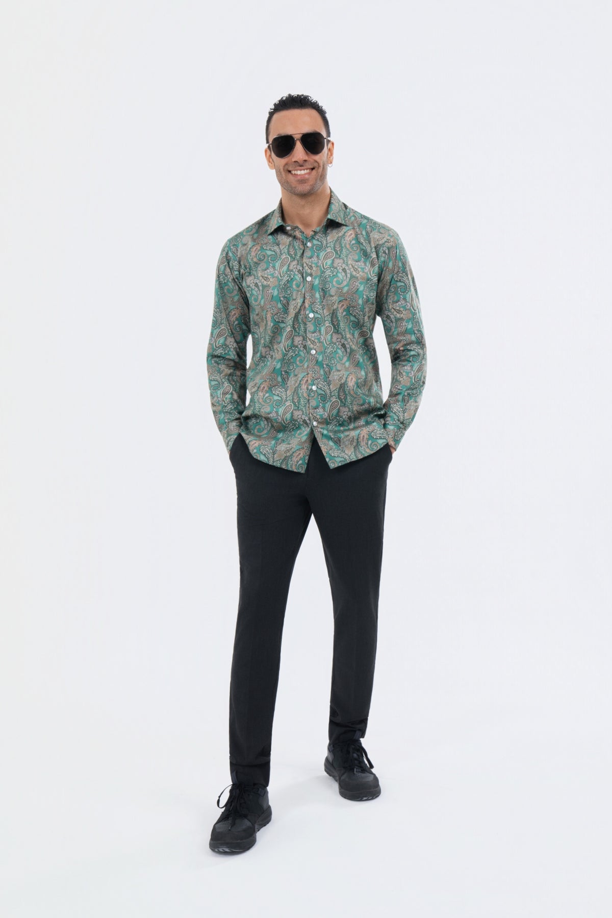 Male model wearing a sage green paisley shirt with black trousers.