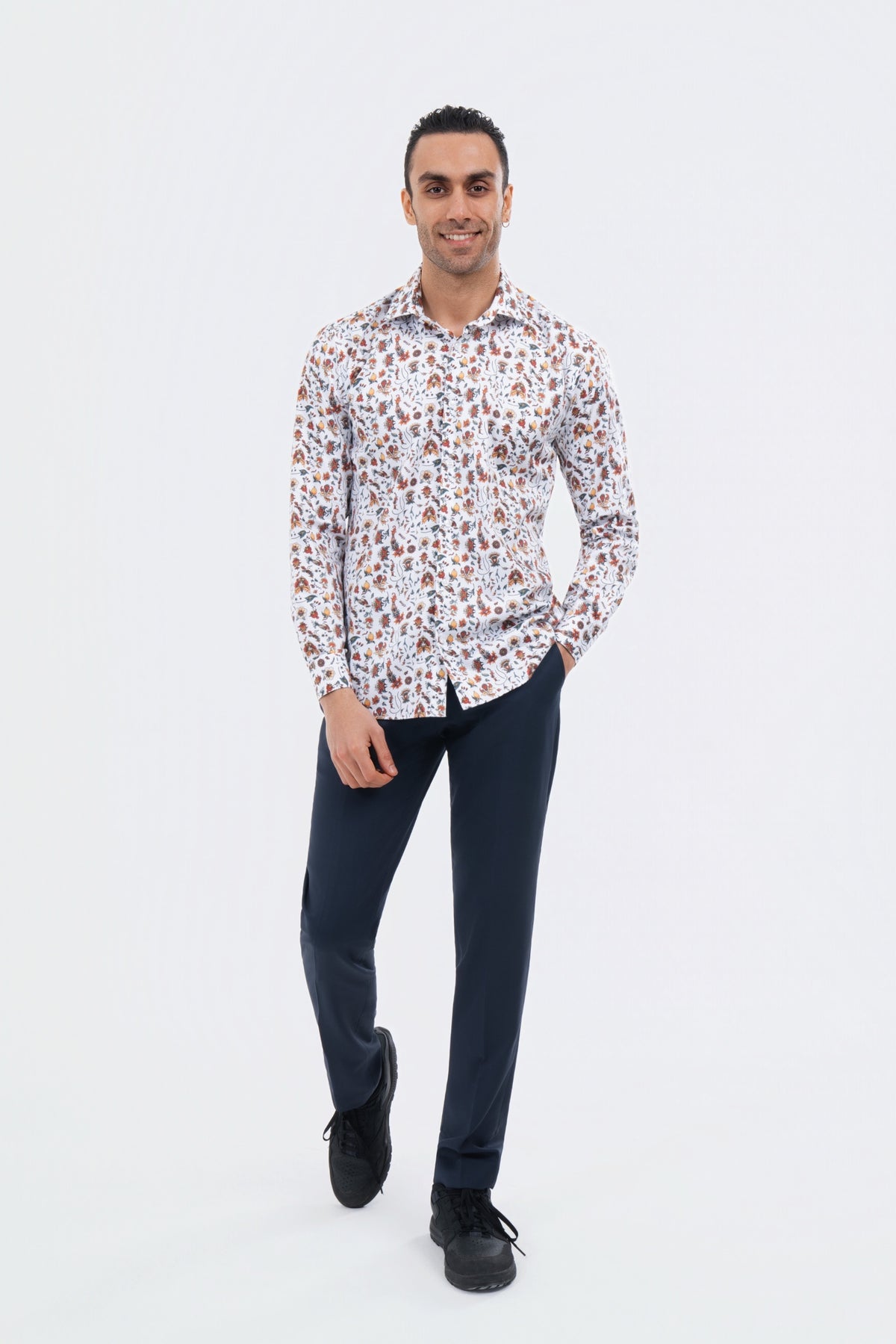 Male model wearing a white multicolour abstract-print shirt with black trousers.