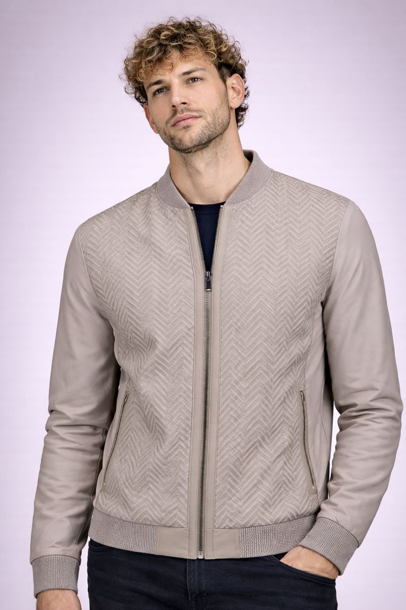Man wearing a beige patterned bomber jacket on a light purple background