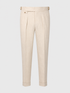 Beige trousers with pleated front details, a button closure, and adjustable belt loops, shown against a light gray background.
