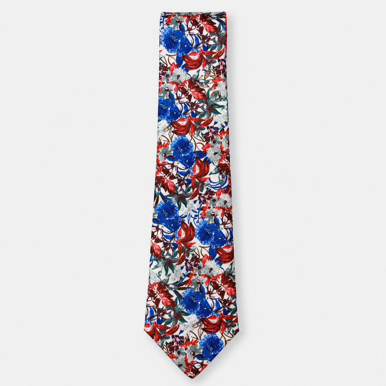 The Assisi Tie, an ivory silk tie with a vivid red, blue and green botanical print on a light grey background.