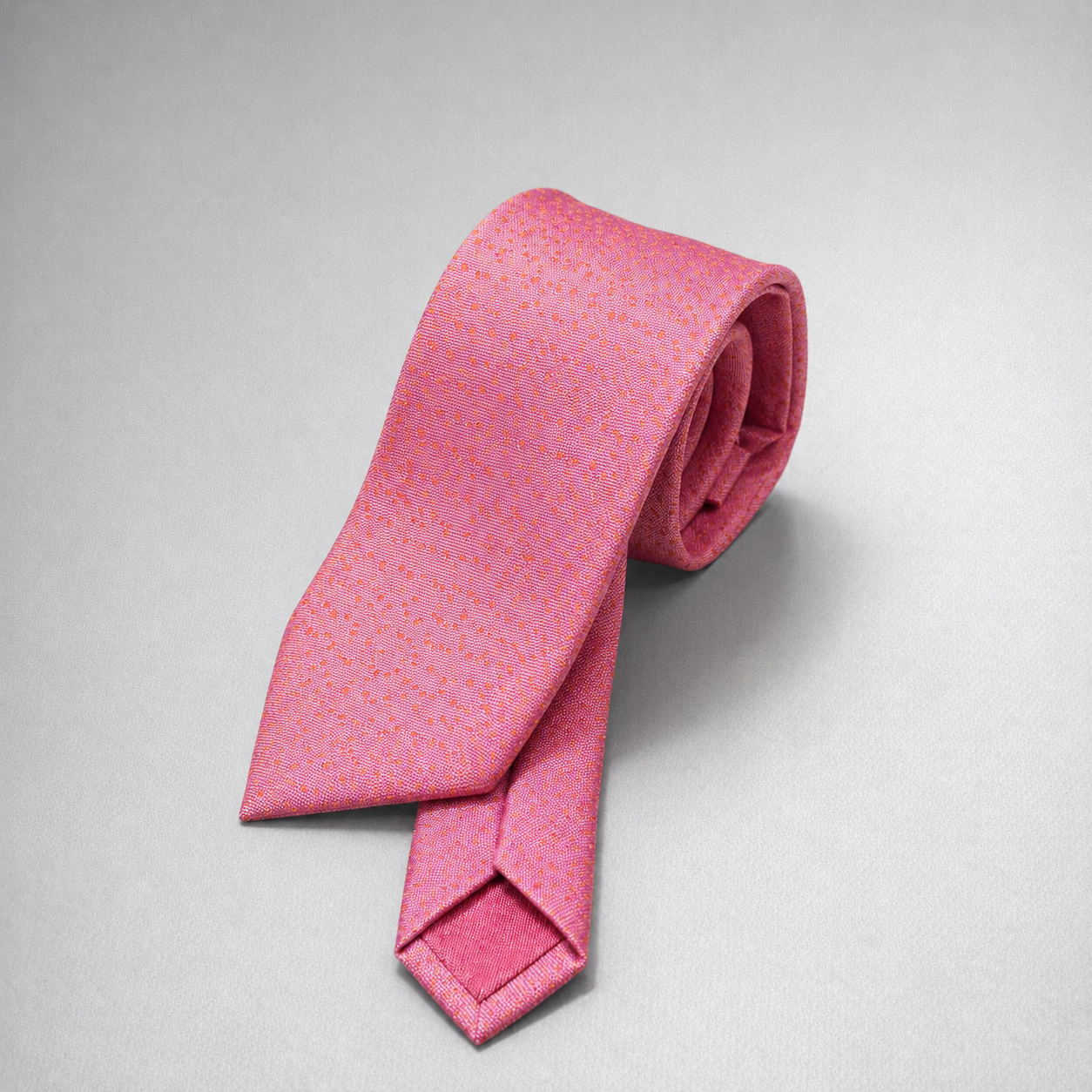 Bright pink textured silk necktie on a grey background.