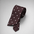 Brown silk necktie with white polka dots on a grey background.