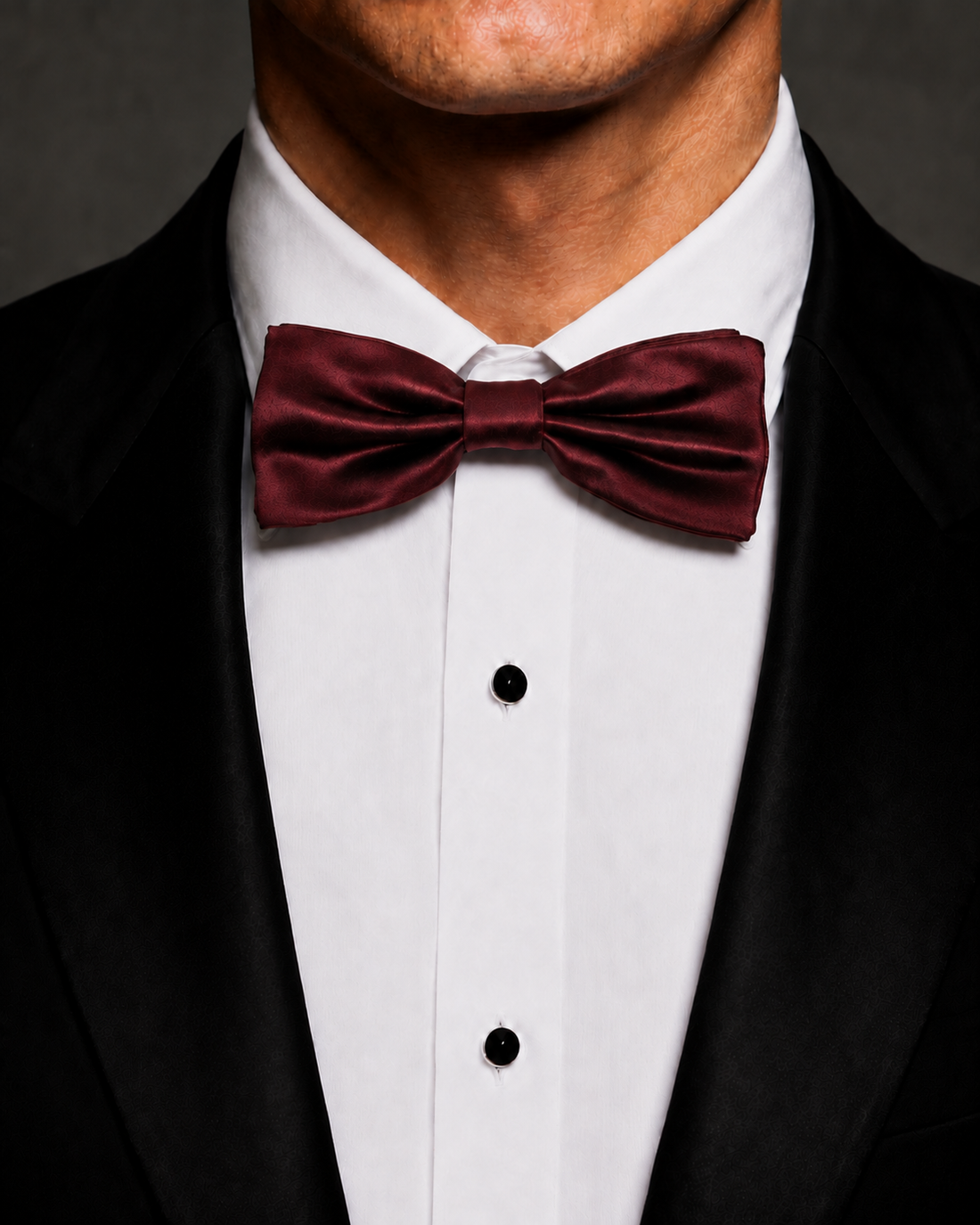 Burgundy silk velvet bow tie worn with a black tuxedo and white dress shirt.