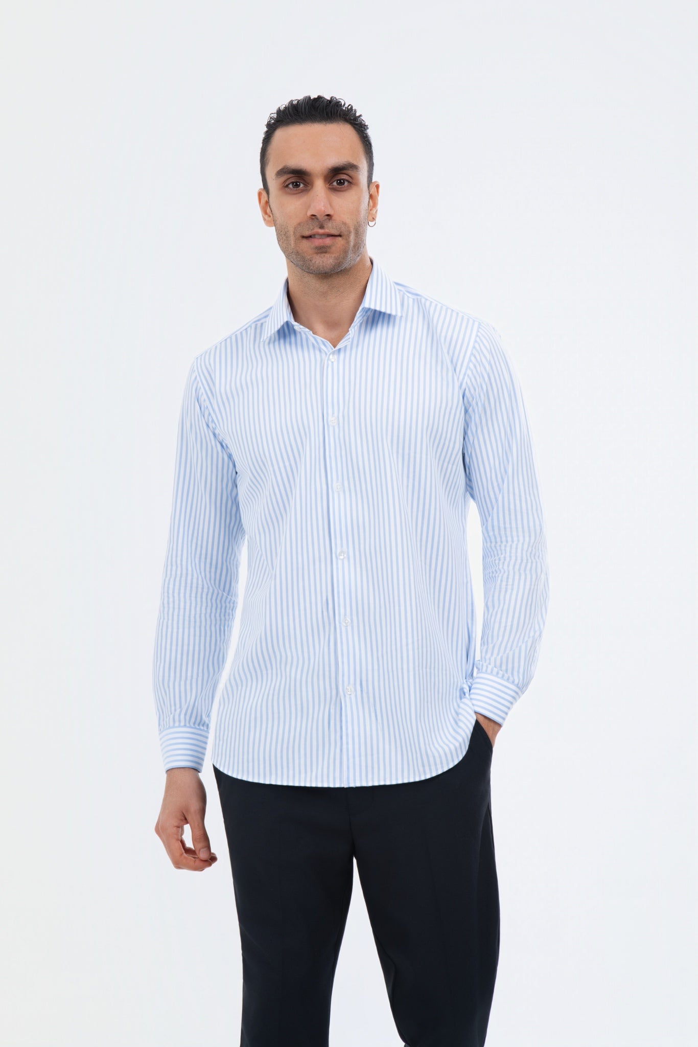 Male model wearing a light blue striped shirt with black trousers in the studio.