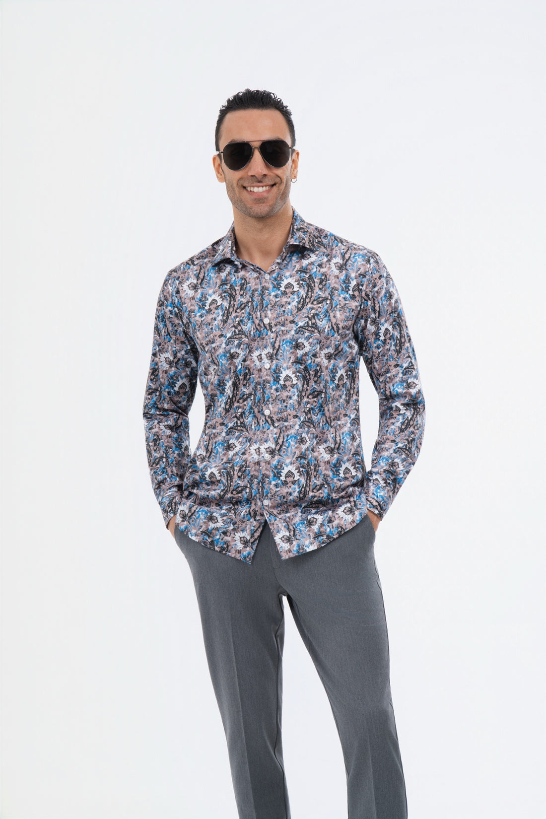 Male model wearing a multicolour paisley shirt with grey trousers in the studio.