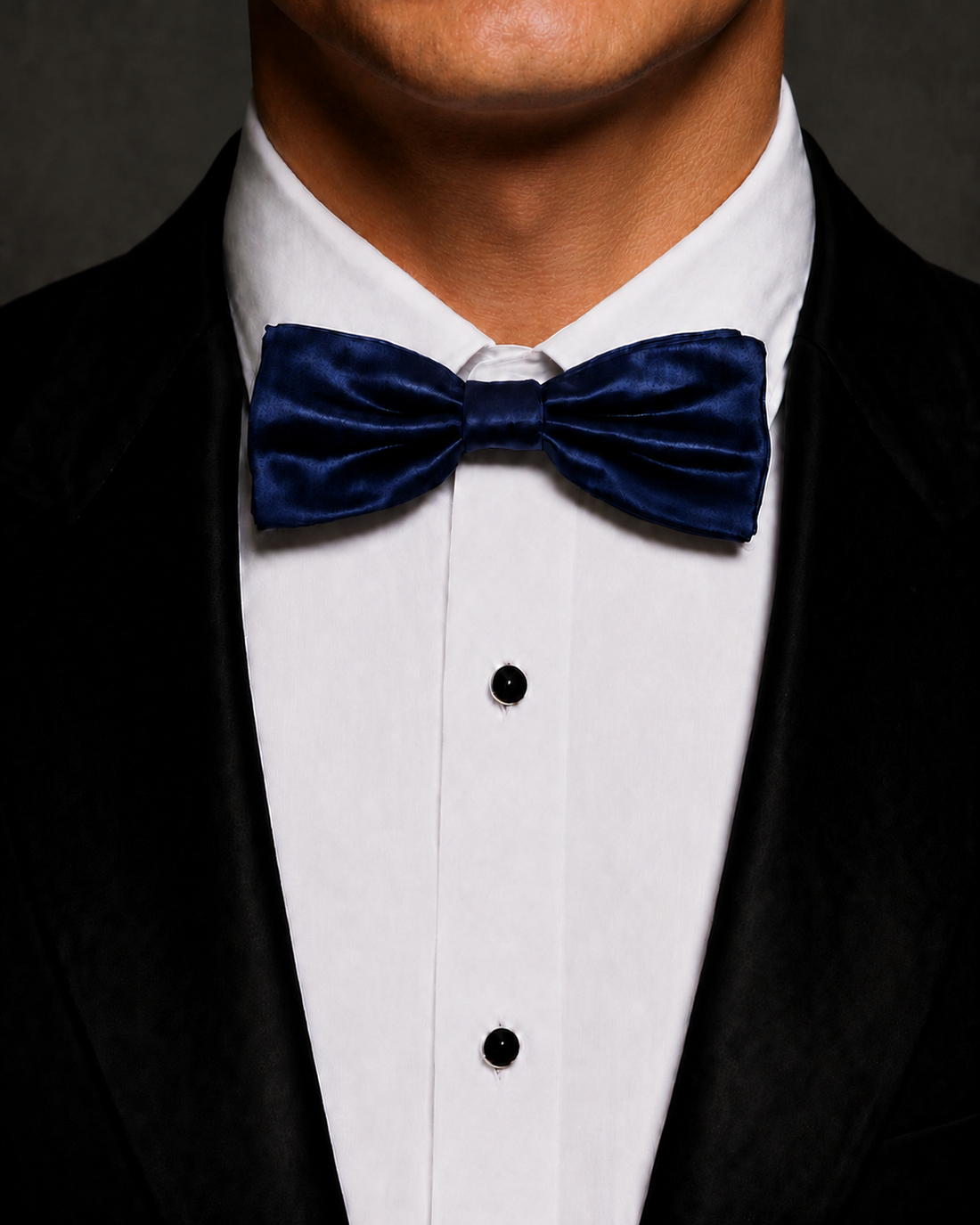 Navy silk velvet bow tie worn with a black tuxedo and white dress shirt.