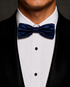 Navy silk velvet bow tie worn with a black tuxedo and white dress shirt.