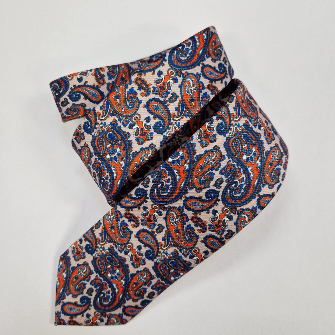 Navy silk tie with small silver paisley motifs, loosely folded.