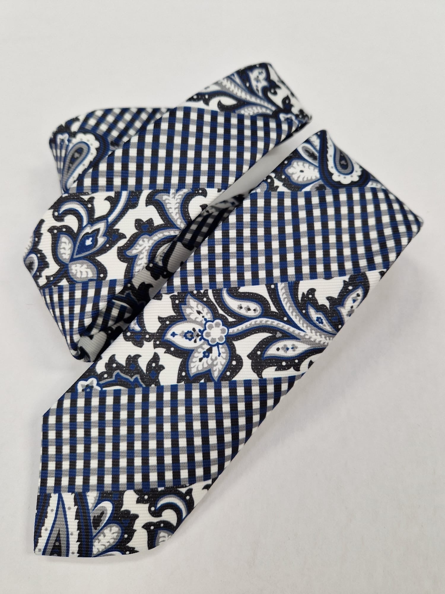 Navy and white floral check silk tie, loosely folded.