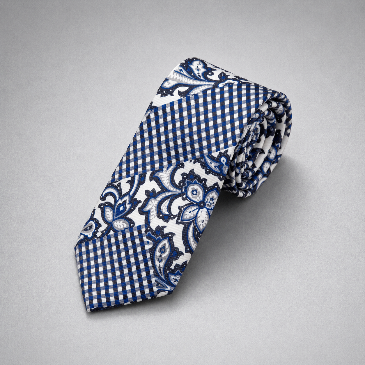 Navy and white geometric floral silk necktie on a grey background.
