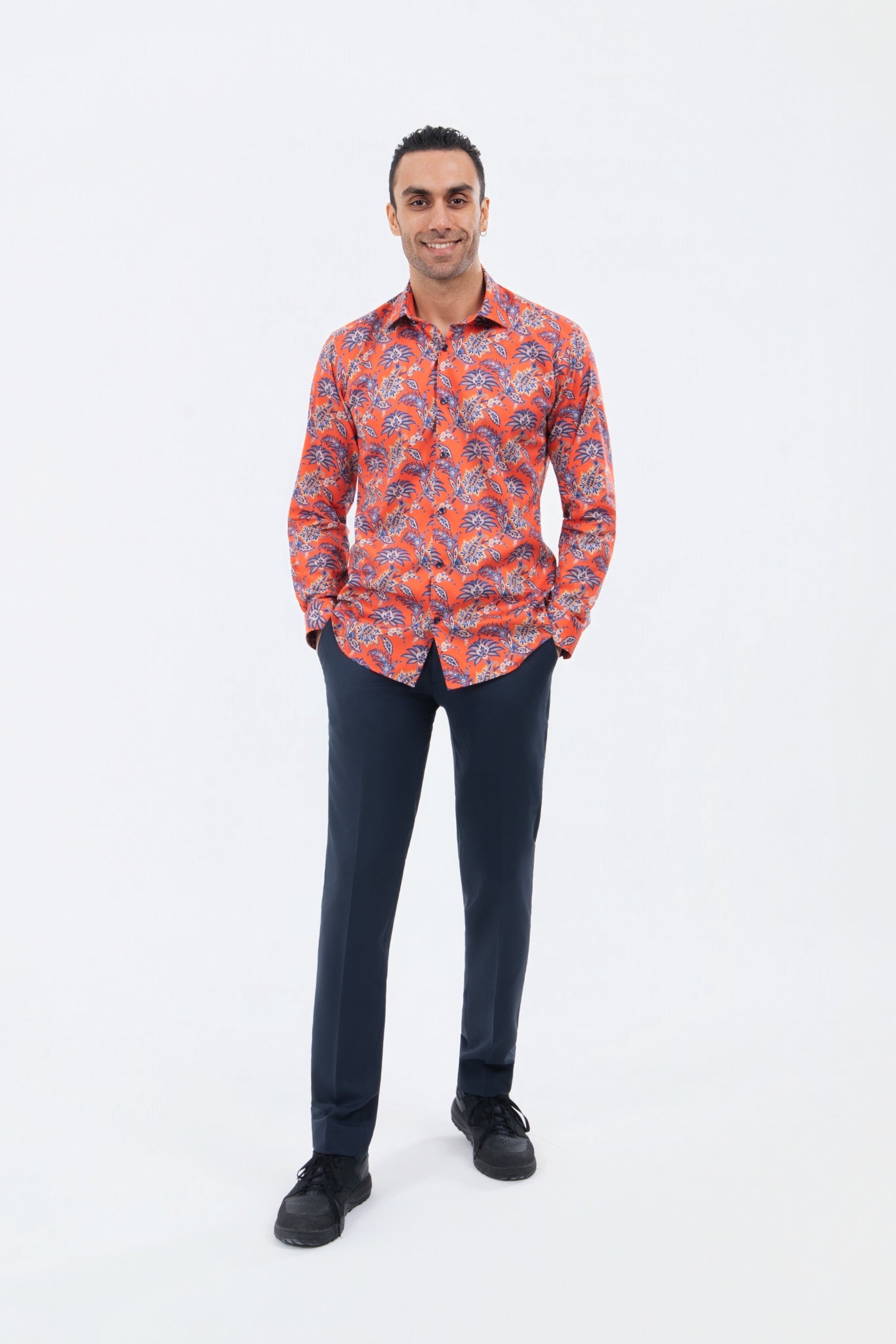 Male model wearing a bright orange paisley shirt with navy trousers.