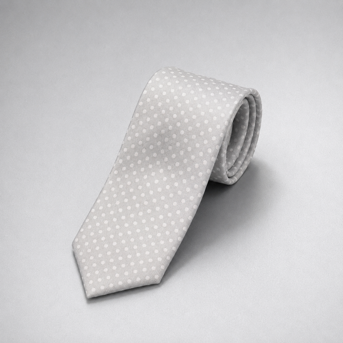 Silver silk necktie with a subtle white dot pattern on a grey background.