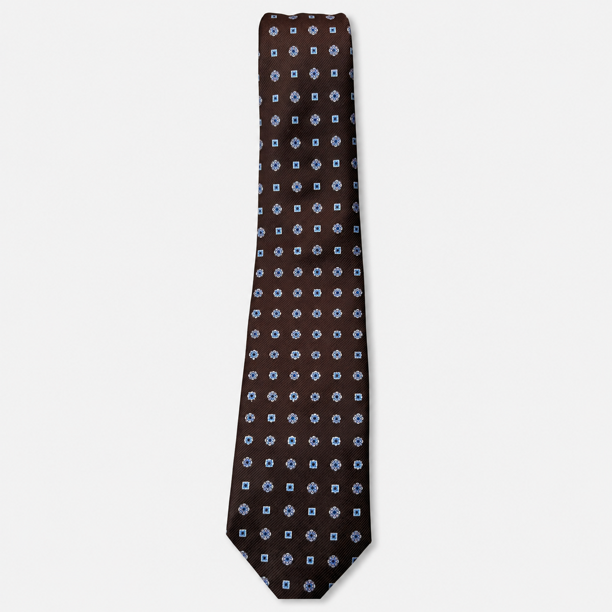 The Trento Tie – brown and light blue dot medallion silk tie on a light grey background