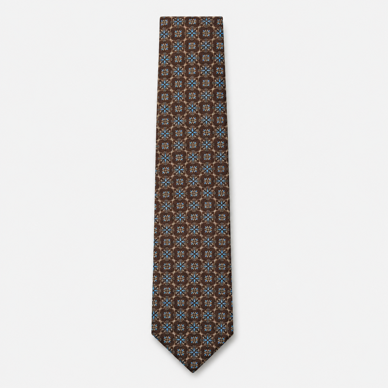The Udine Tie – rust brown and blue geometric floral silk tie on a light grey background