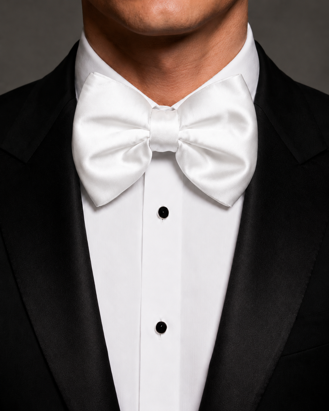 White jumbo butterfly silk bow tie worn with a black tuxedo and white dress shirt.