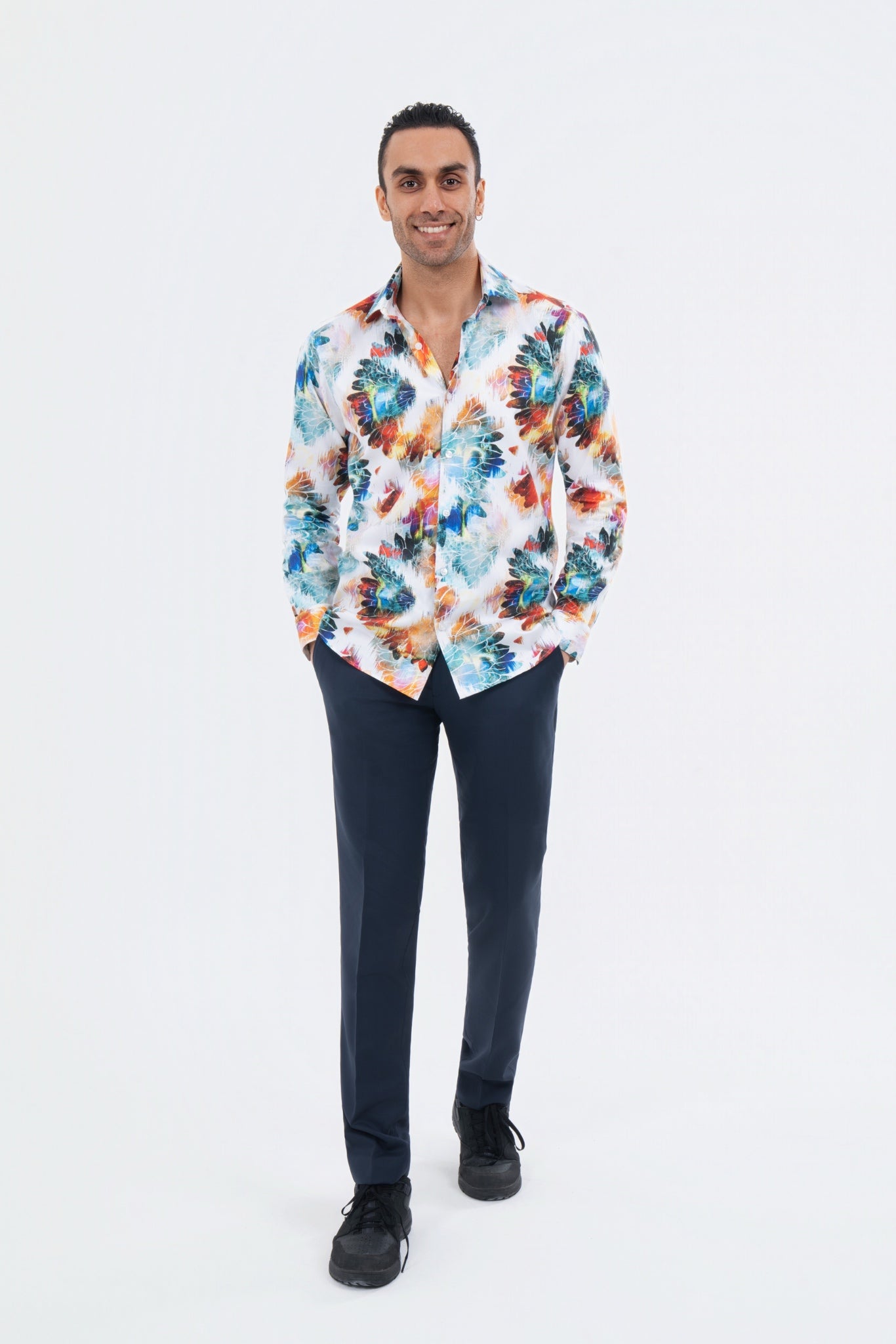 Male model wearing a white multicolour tropical-print shirt with black trousers.